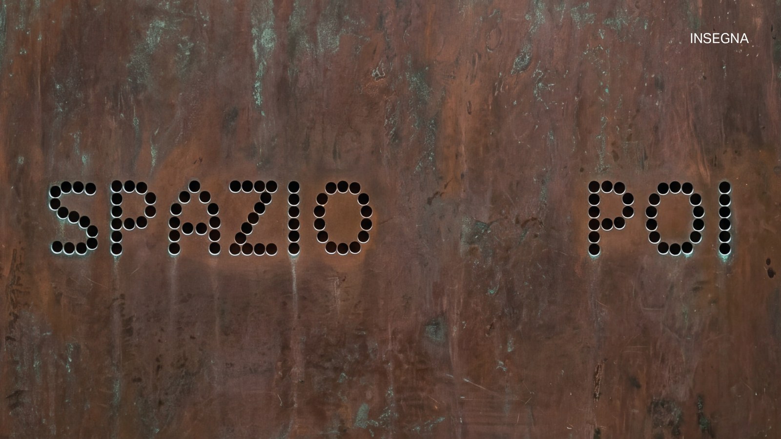 L'insegna di Spazio Poi: il logo a pallini forato in una lastra di metallo ossidato